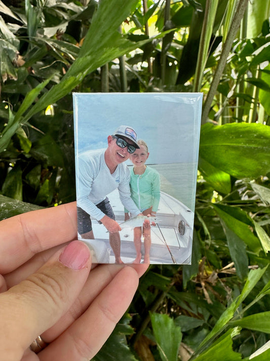 A custom photo magnet featuring a father and daughter holding a bone fish.  There are palm trees in the background